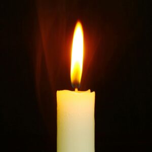 Collections A single candle burning brightly in the dark, symbolizing light and hope.